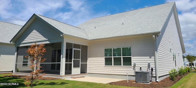 rear view of house with cooling unit, a yard, a sunroom, and a patio