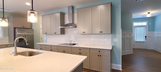 kitchen with sink, stainless steel fridge with ice dispenser, hanging light fixtures, gray cabinets, and wall chimney range hood