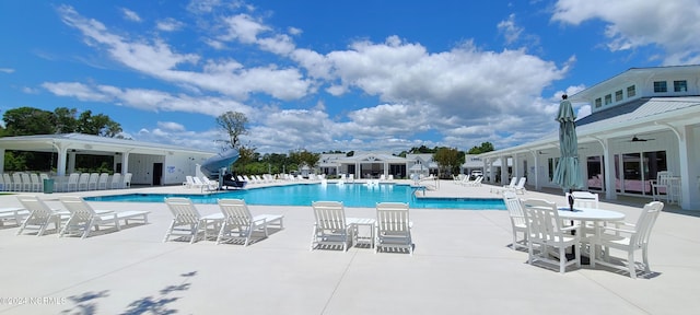 view of swimming pool featuring a patio, a water slide, and ceiling fan