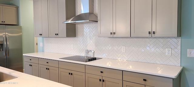 kitchen featuring black electric stovetop, wall chimney exhaust hood, stainless steel fridge with ice dispenser, and backsplash