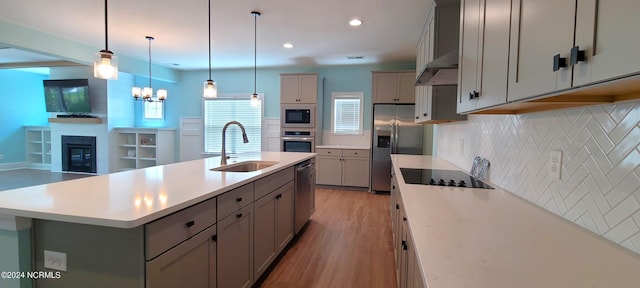 kitchen featuring sink, gray cabinetry, a kitchen island with sink, and black appliances