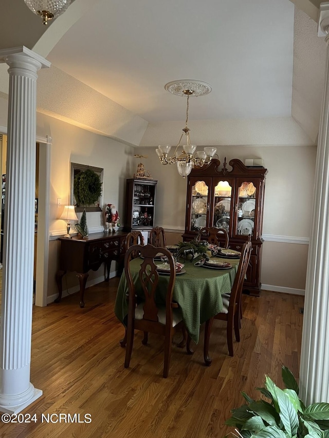 dining space with an inviting chandelier, hardwood / wood-style flooring, decorative columns, and lofted ceiling