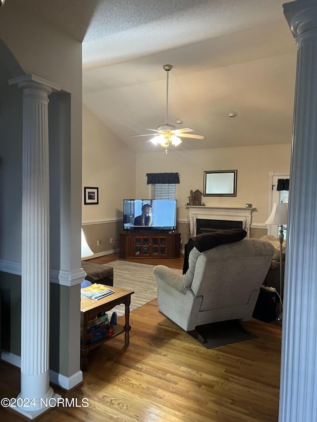 living room with hardwood / wood-style flooring, ceiling fan, vaulted ceiling, and ornate columns