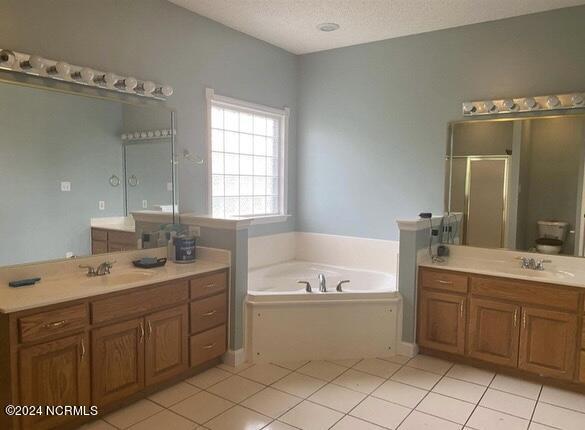 full bathroom featuring tile patterned floors, toilet, separate shower and tub, a textured ceiling, and vanity