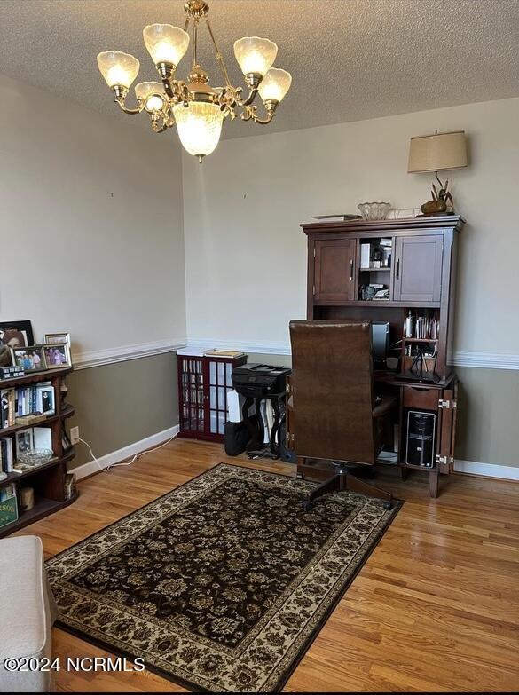 home office featuring an inviting chandelier, hardwood / wood-style flooring, and a textured ceiling