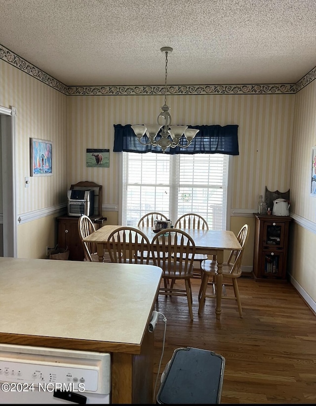 dining area featuring an inviting chandelier, dark wood-type flooring, and a textured ceiling