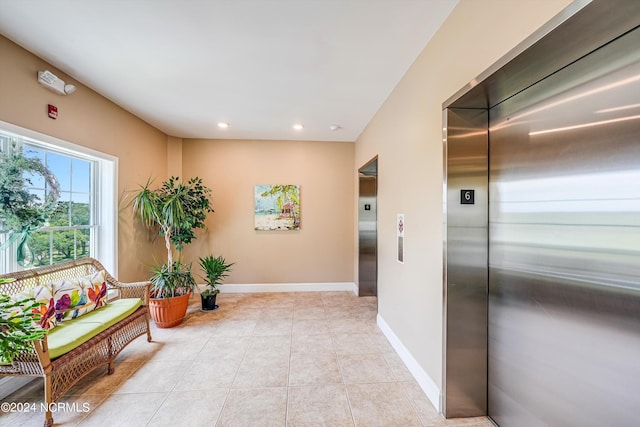 corridor featuring elevator and light tile patterned flooring