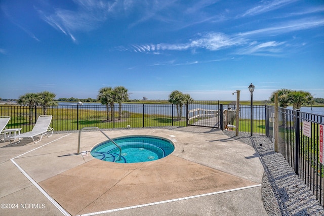 view of pool with a community hot tub, a patio, and a water view