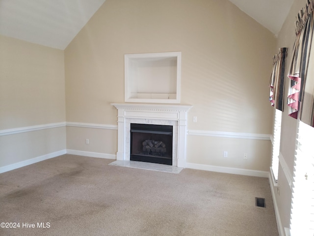 unfurnished living room with a high end fireplace, light colored carpet, and lofted ceiling