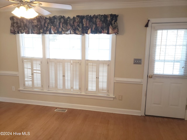 interior space featuring wood-type flooring, ceiling fan, and ornamental molding