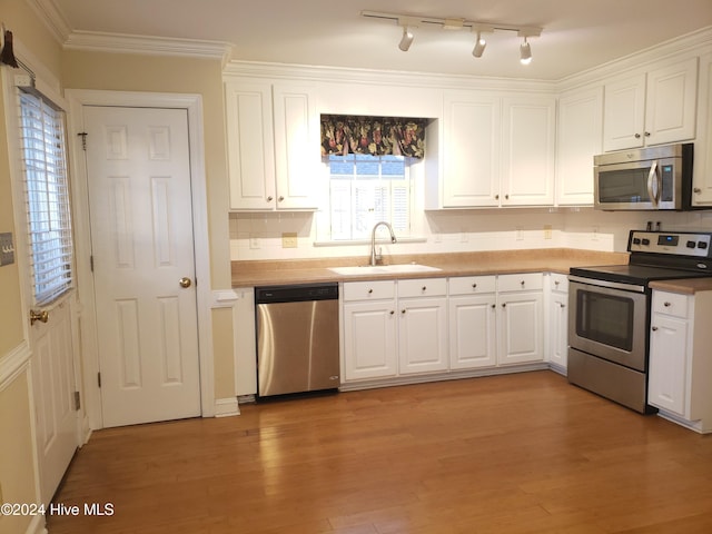 kitchen with sink, light hardwood / wood-style flooring, crown molding, white cabinets, and appliances with stainless steel finishes