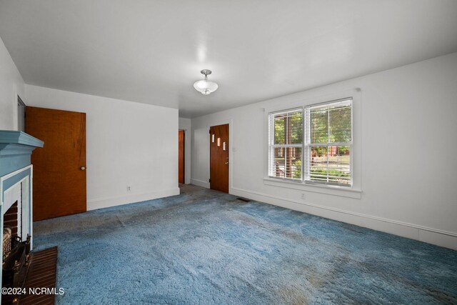 unfurnished living room featuring carpet and a brick fireplace