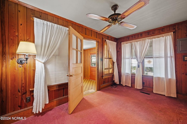 interior space featuring ceiling fan, carpet floors, and wooden walls