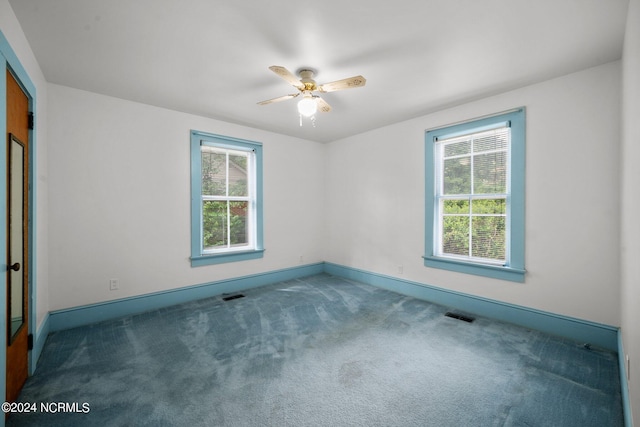 empty room with ceiling fan, dark carpet, and a wealth of natural light