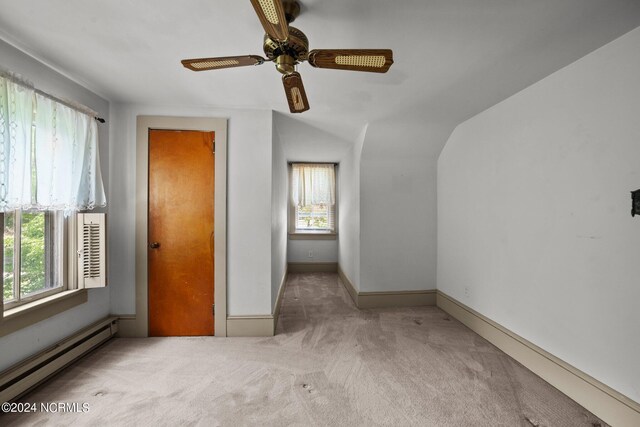 unfurnished bedroom featuring ceiling fan, a baseboard radiator, lofted ceiling, and light carpet