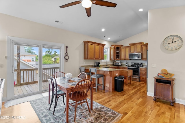 dining room with ceiling fan, lofted ceiling, sink, and light wood-type flooring