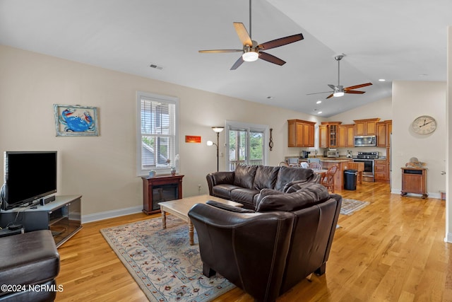 living room with ceiling fan, vaulted ceiling, and light hardwood / wood-style flooring