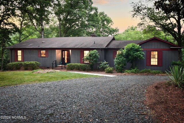 view of front of property with a front lawn, a chimney, and gravel driveway