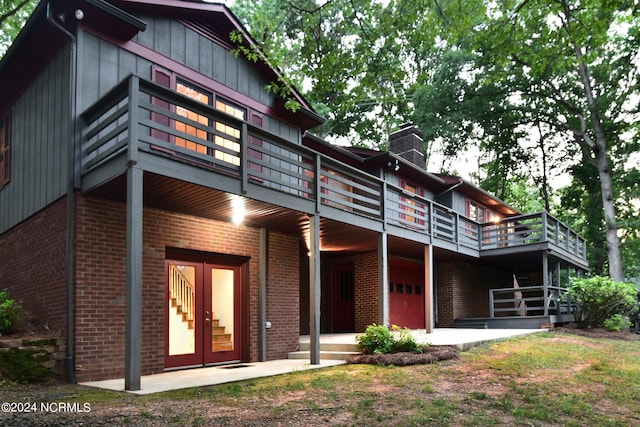 rear view of property with a garage, a chimney, and brick siding