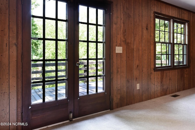 entryway with carpet floors, wood walls, and visible vents