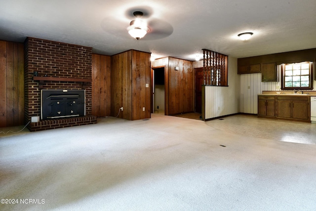 unfurnished living room with wood walls, a brick fireplace, and a sink