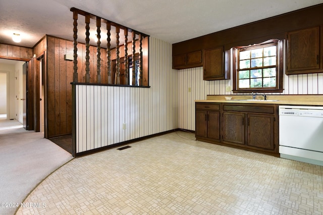 kitchen featuring light countertops, dishwasher, a sink, and dark brown cabinets