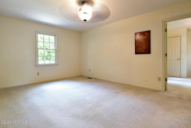 unfurnished room with baseboards, a textured ceiling, and light colored carpet