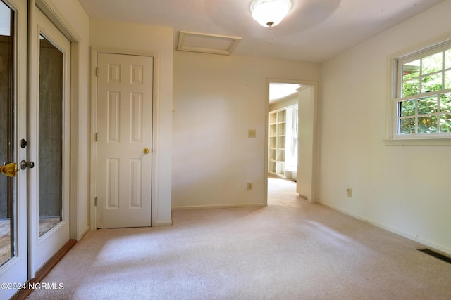 unfurnished room featuring attic access, visible vents, light carpet, and baseboards