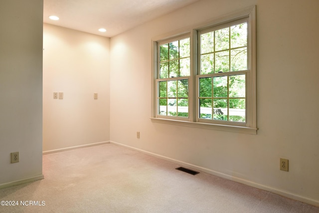 unfurnished room with light carpet, a wealth of natural light, visible vents, and baseboards