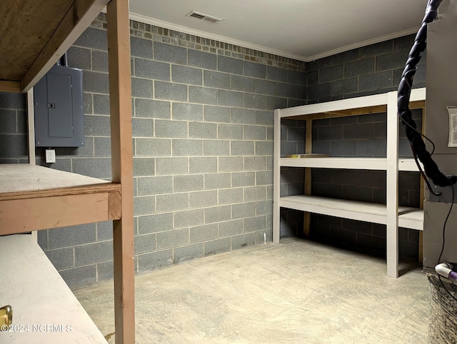 basement with crown molding, electric panel, and concrete block wall