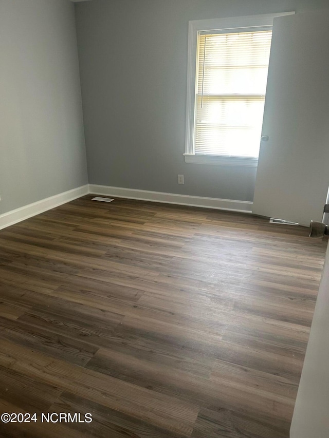 empty room featuring baseboards and dark wood-style flooring