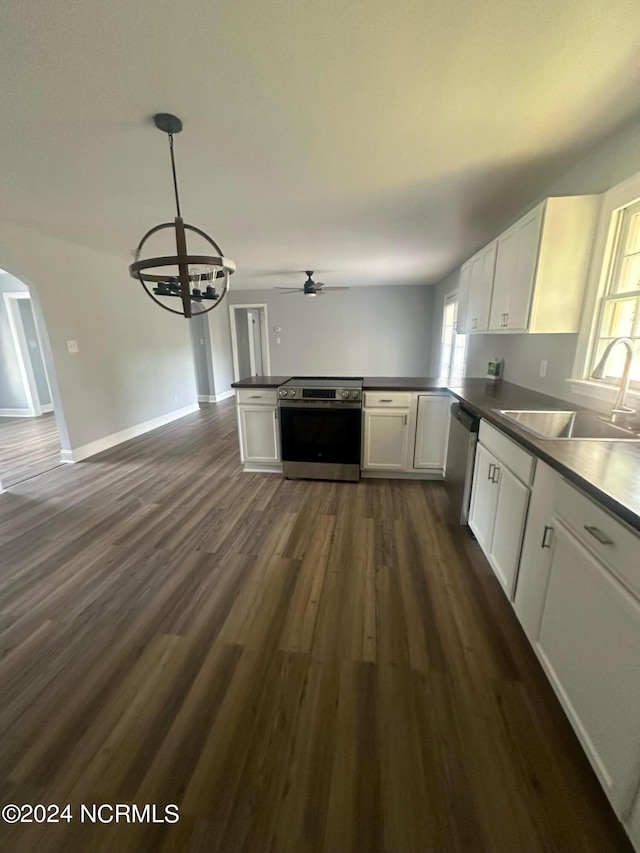 kitchen with arched walkways, stainless steel appliances, dark wood-style flooring, a sink, and white cabinets