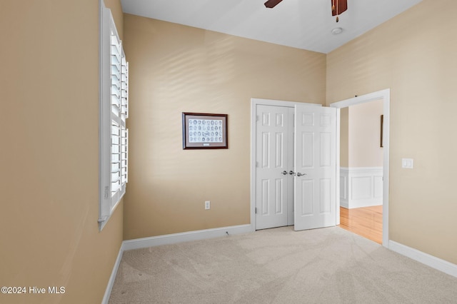 unfurnished bedroom featuring ceiling fan, a closet, and light colored carpet