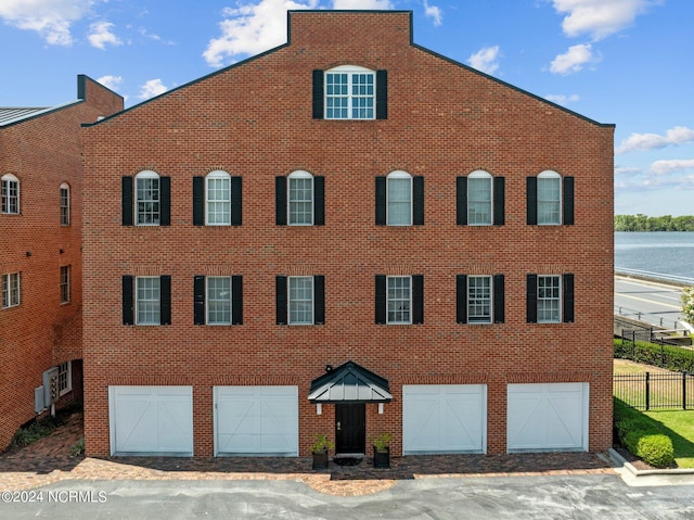 view of front of home with an attached garage, fence, and brick siding