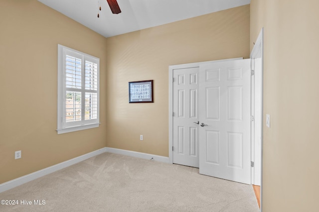 unfurnished bedroom with ceiling fan, light carpet, and a closet