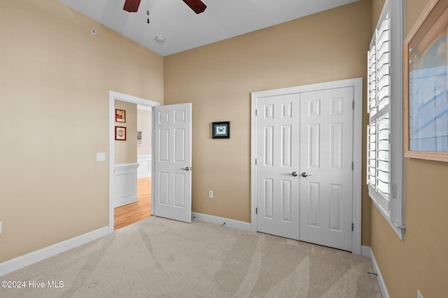 unfurnished bedroom featuring carpet floors, a closet, a ceiling fan, and baseboards