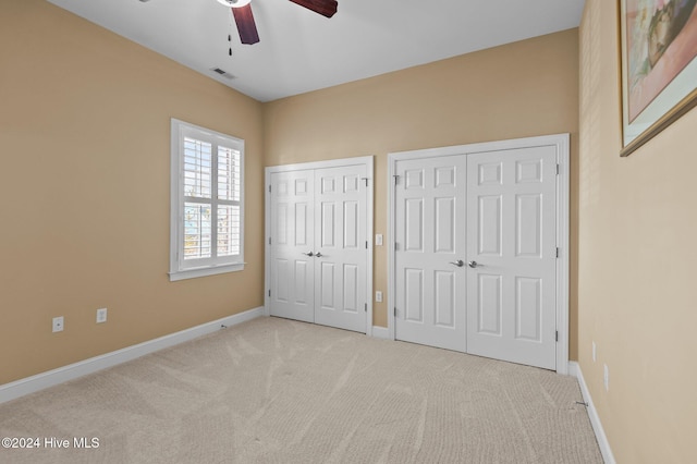 unfurnished bedroom featuring multiple closets, carpet, visible vents, and baseboards