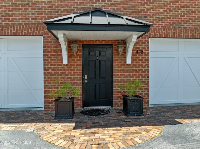 entrance to property with brick siding and an attached garage