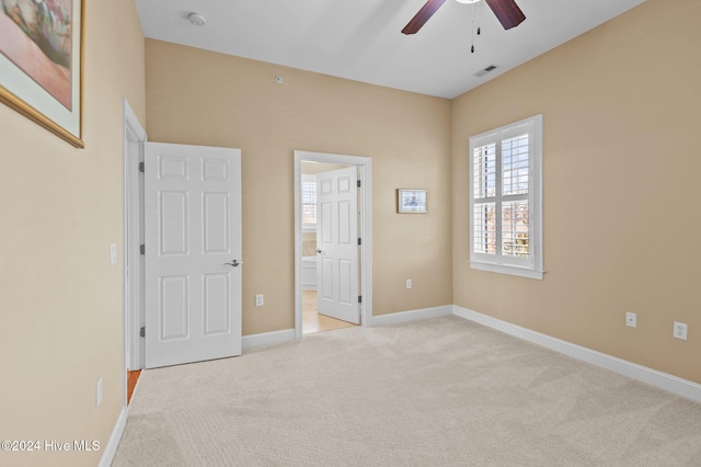 unfurnished bedroom featuring light carpet, baseboards, visible vents, connected bathroom, and ceiling fan