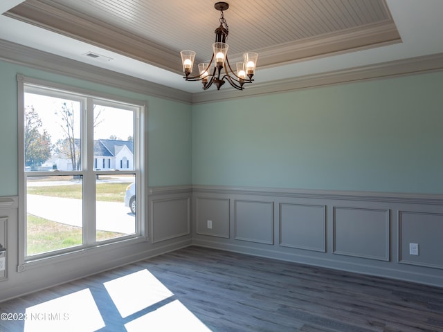 spare room with dark hardwood / wood-style floors, an inviting chandelier, ornamental molding, and a tray ceiling