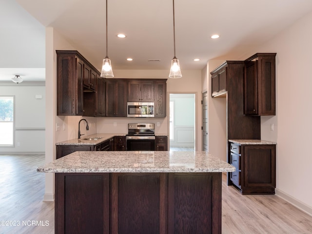 kitchen featuring sink, dark brown cabinetry, appliances with stainless steel finishes, and hanging light fixtures