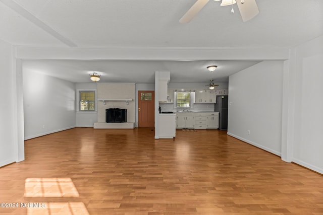 unfurnished living room featuring a fireplace, light hardwood / wood-style floors, and ceiling fan