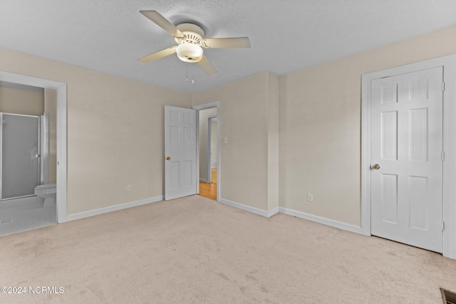 unfurnished bedroom featuring ceiling fan, light carpet, and ensuite bath