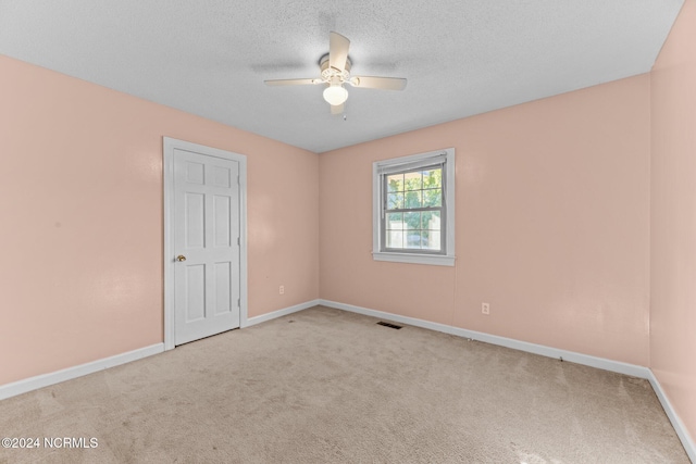 spare room with ceiling fan, light colored carpet, and a textured ceiling