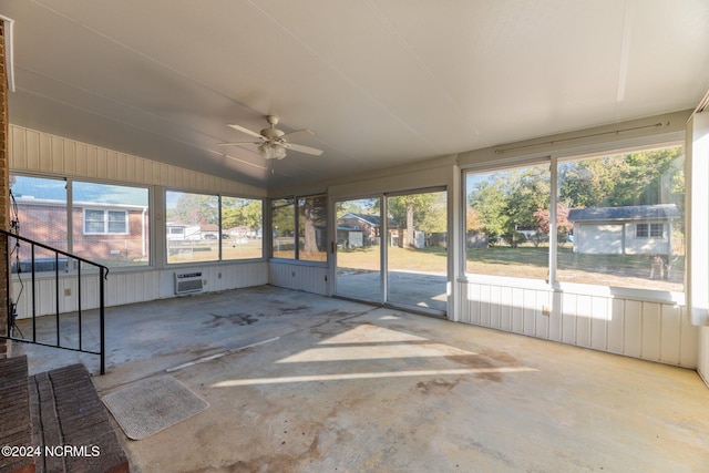 unfurnished sunroom with vaulted ceiling, a wall unit AC, a wealth of natural light, and ceiling fan