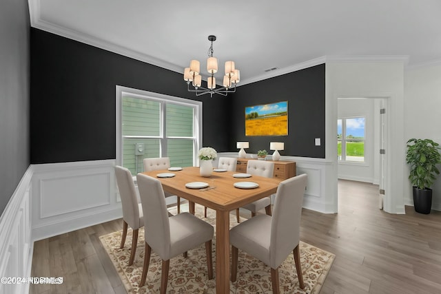 dining space with a chandelier, visible vents, light wood-style floors, ornamental molding, and wainscoting