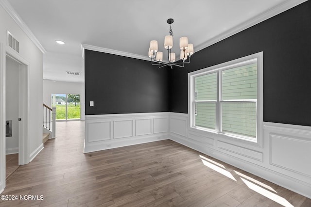 empty room featuring stairs, wood finished floors, visible vents, and a notable chandelier