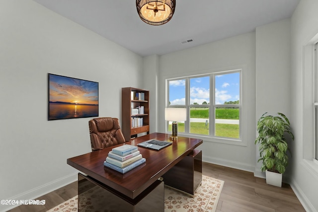 office space with baseboards, visible vents, and wood finished floors