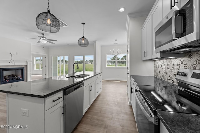 kitchen featuring a center island with sink, decorative backsplash, appliances with stainless steel finishes, open floor plan, and a sink