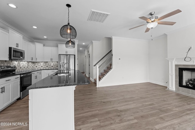 kitchen with visible vents, appliances with stainless steel finishes, light wood-style flooring, and a tiled fireplace